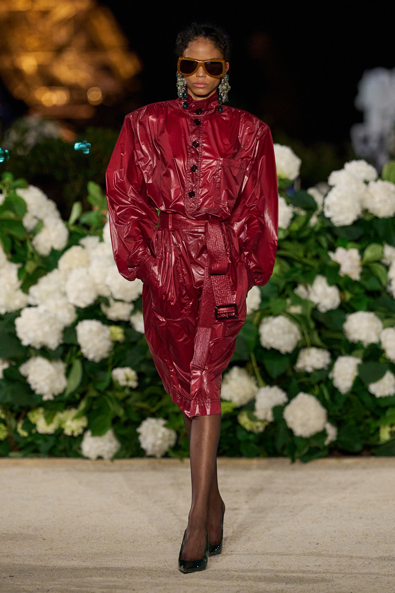 A model walking in the S/S 26 Saint Laurent show in Paris wearing a burgundy trench coat as a dress.
