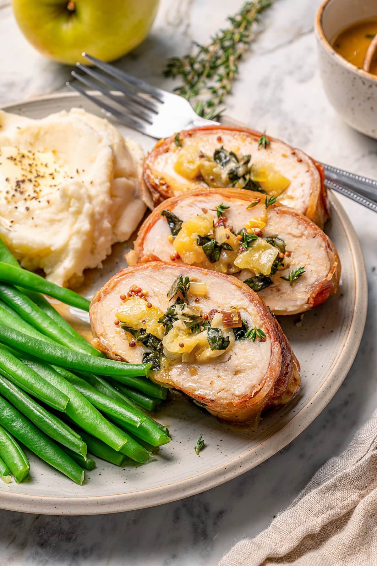 This Prosciutto Wrapped Stuffed Turkey Tenderloin recipe is filled with apples, cheese and kale for a healthy high-protein dinner. Delicious! Three slices of prosciutto-wrapped stuffed turkey tenderloin with kale and apple.