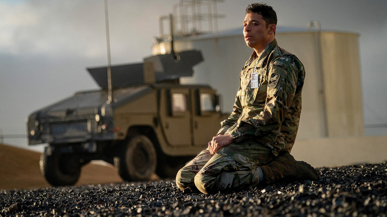 Anthony Ramos as Major Daniel Gonzalez kneeling on the ground with a humvee in the background in A House of Dynamite