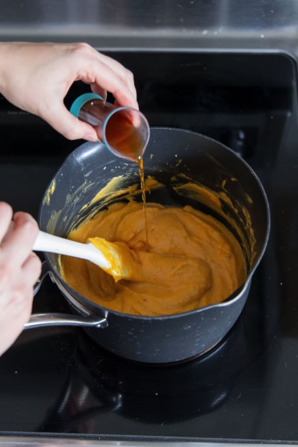 Adding bourbon and vanilla to cooked custard.
