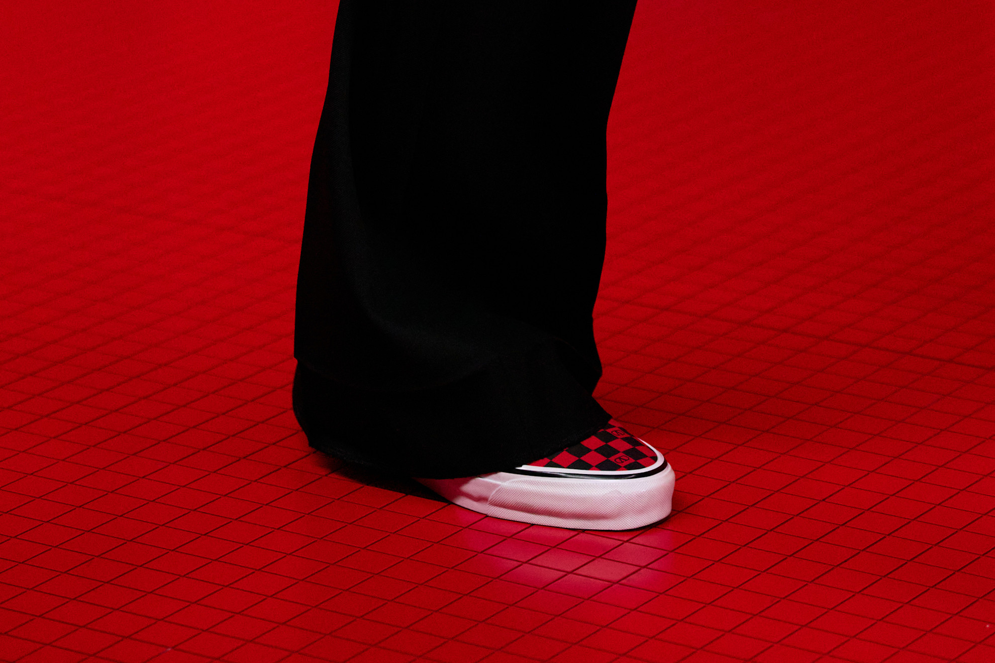 An image of the Valentino autumn/winter 2025 shoe. The model wears black trousers with red checkered vans.