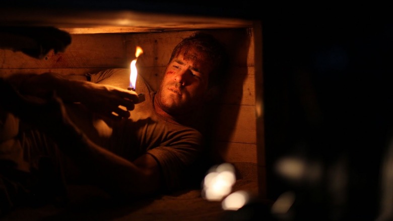Paul Conroy holding a cigarette lighter in Buried