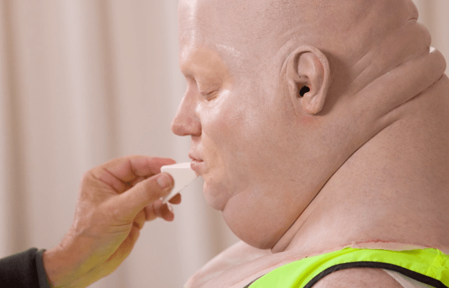 Still of Brennan Lee Mulligan having a giant baby head applied in the 'Last Looks' featurette for 'Very Important People' Season 3