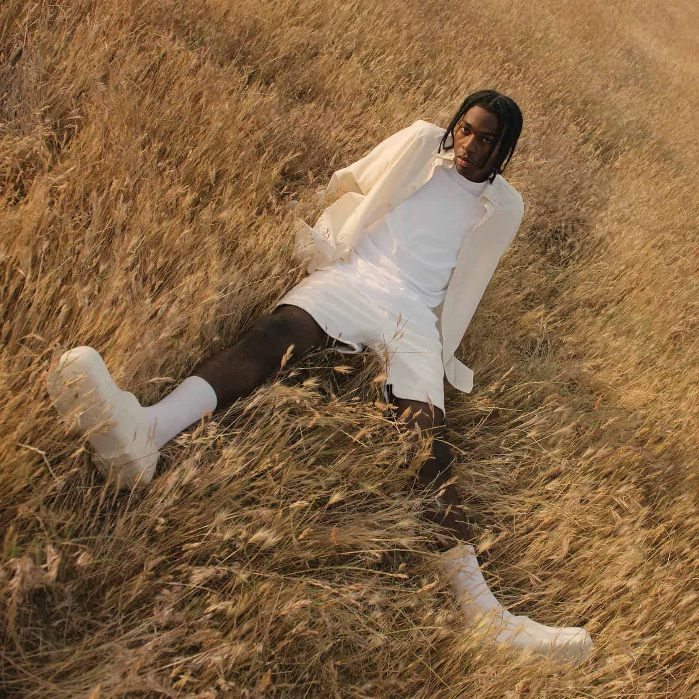 Man in the grass field wearing off white athleisure outfit