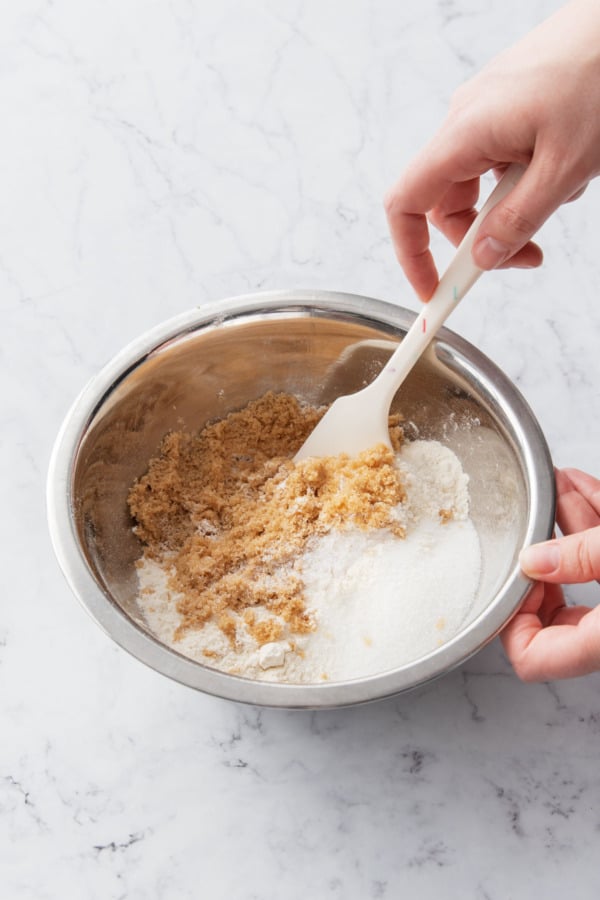 Making the crumb topping by combining sugar, flour, and salt in a metal mixing bowl.