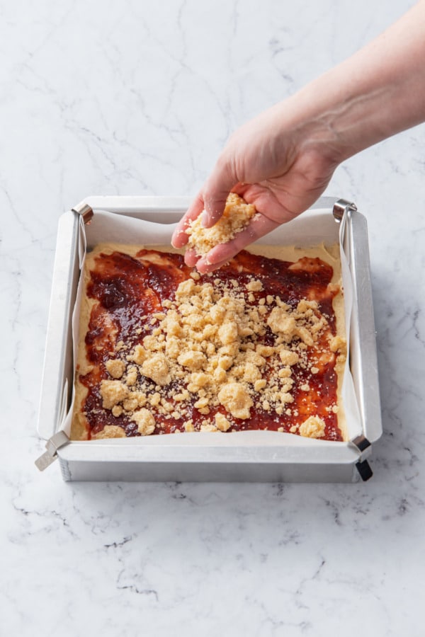 Sprinkling crumb mixture on top of cake batter and jam layers before baking it.