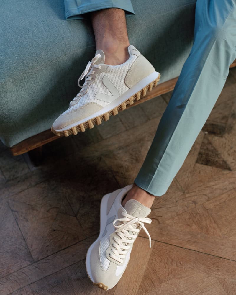 man sitting on a couch wearing a veja rubber trimmed alveomesh sneakers