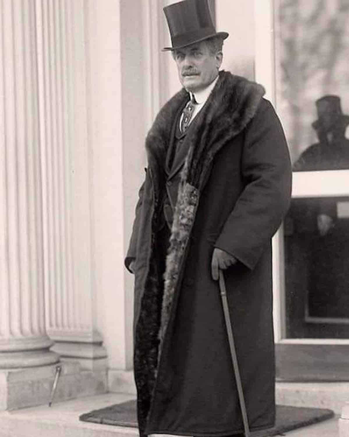 man in 1920s wearing a long coat with fur collar