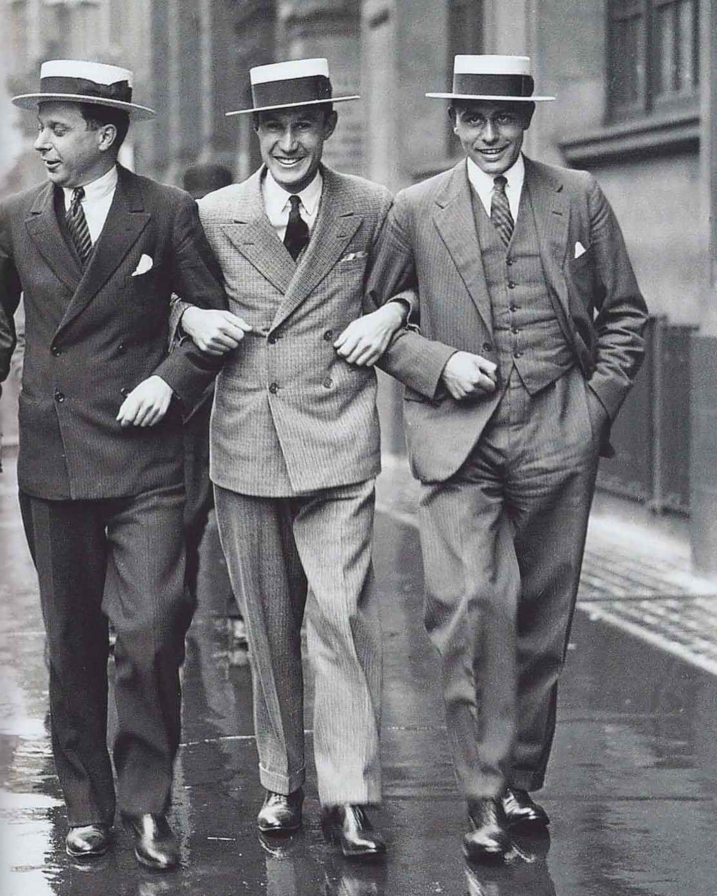 three men in suits walking with arms locked