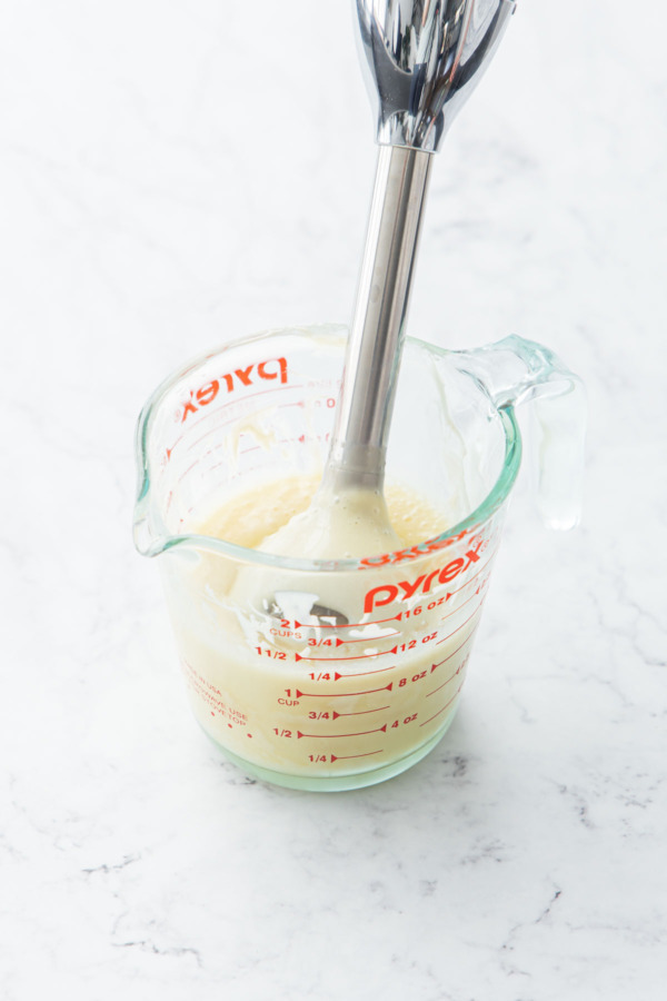 Immersion blender mixing the ganache until smooth and emulsified.