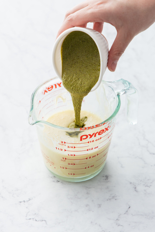 Pouring pistachio butter into container along with melted white chocolate and cream.