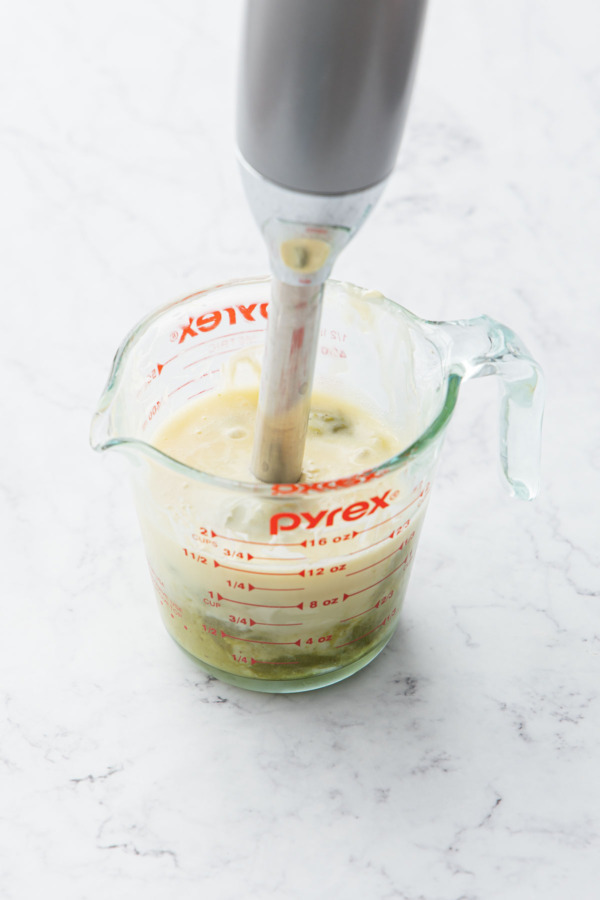 Blending pistachio butter into white chocolate ganache using an immersion blender.