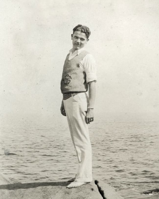 man in 1920s wearing a knitted vest standing by the sea