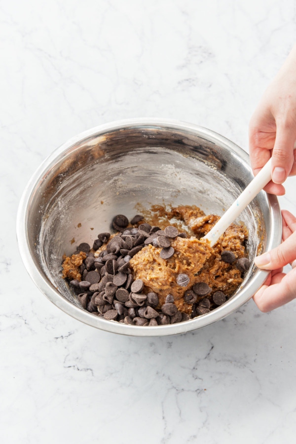Folding chocolate chips into brown butter cookie dough.