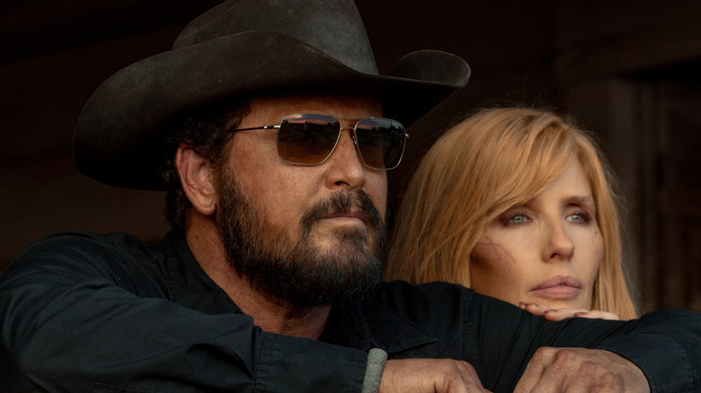 Cole Hauser's Rip Wheeler looks off into the distance wearing shades next to Kelly Reilly's Beth Dutton in Dutton Ranch