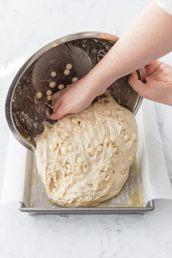 Dumping the risen focaccia dough into the prepared baking pan.