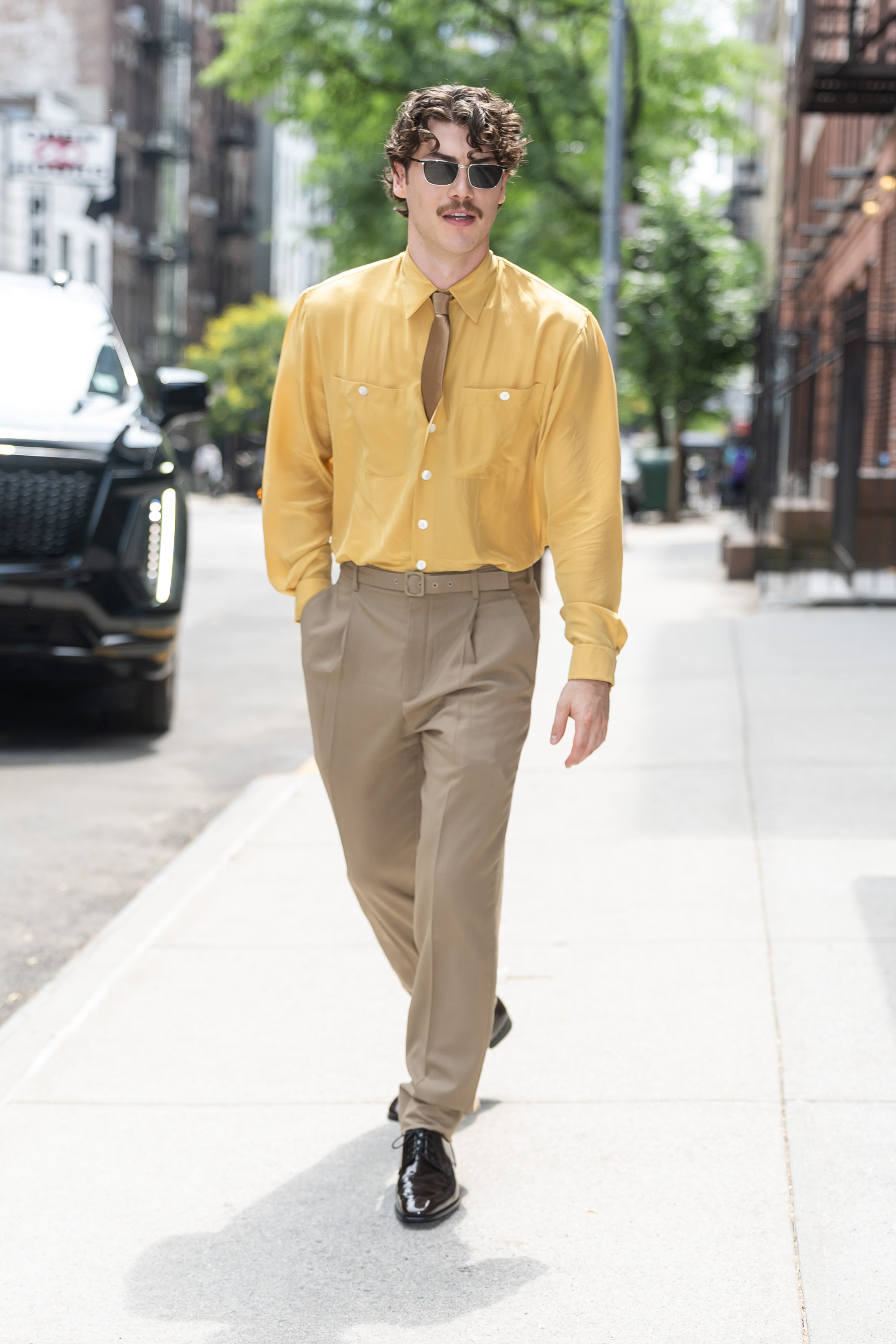 jack innanen wears a yellow button down, tan pants, and black loafers