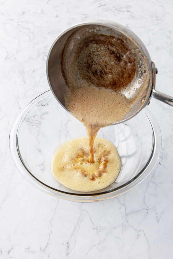 Pouring brown butter into a glass mixing bowl.