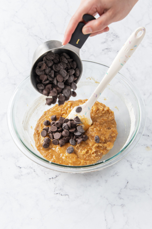 Adding chocolate chips to cookie dough batter.