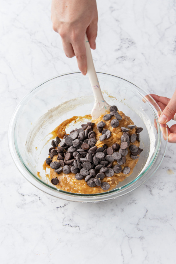 Stirring chocolate chips into cookie dough.