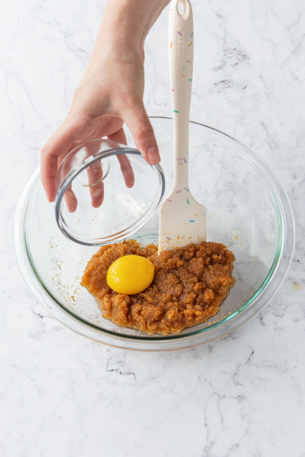 Adding egg yolk to mixing bowl along with butter and sugars.