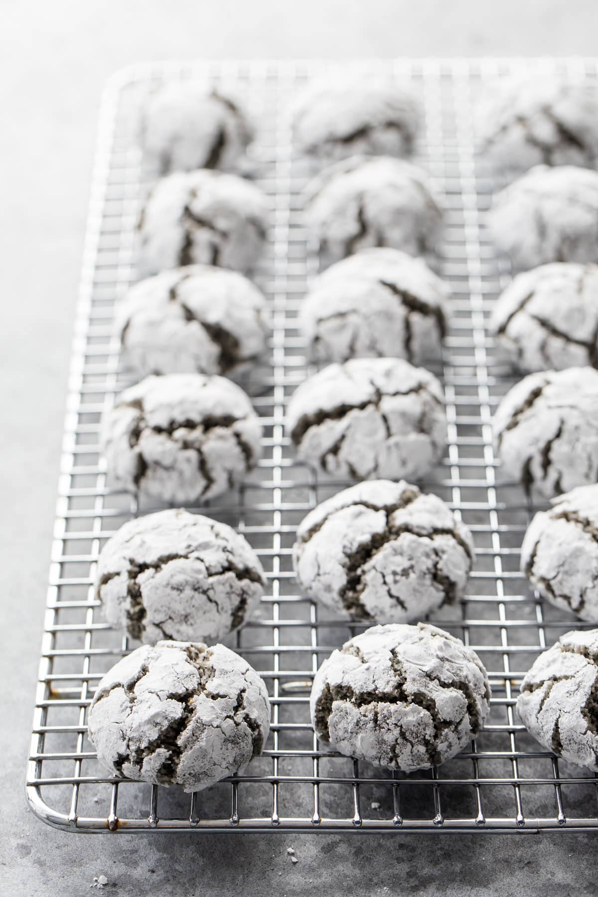 Black Sesame Almond Amaretti Cookies arranged in neat rows on a silver wire cooling rack.