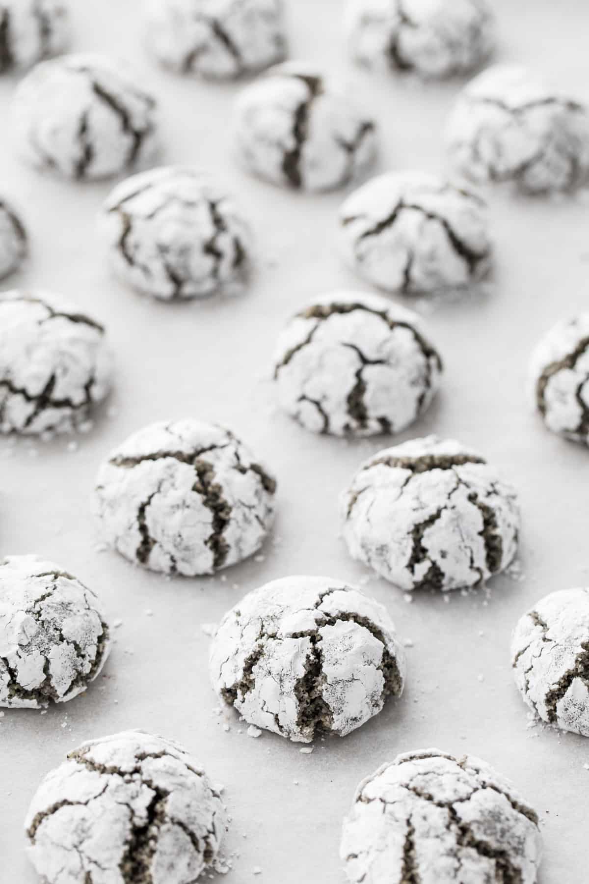 Rows of Black Sesame Amaretti Cookies on a parchment paper-lined baking sheet just out of the oven.