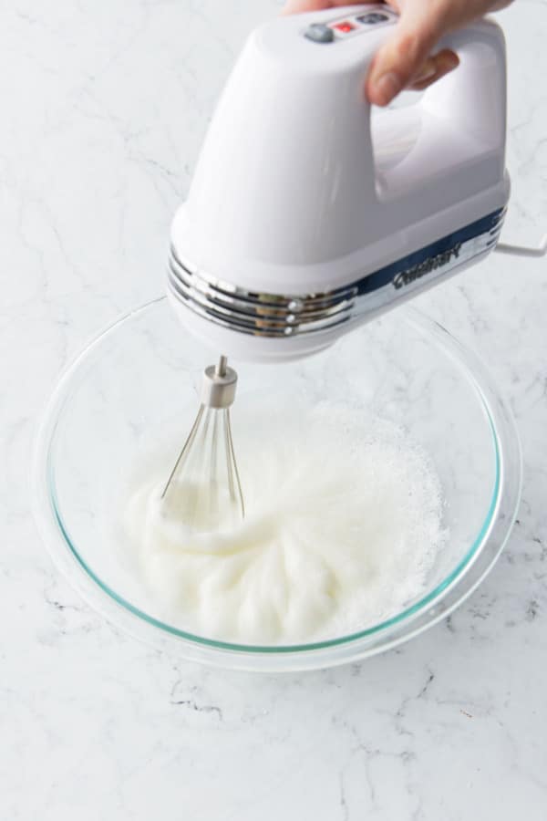 Whipping egg whites until they hold medium-soft peaks.