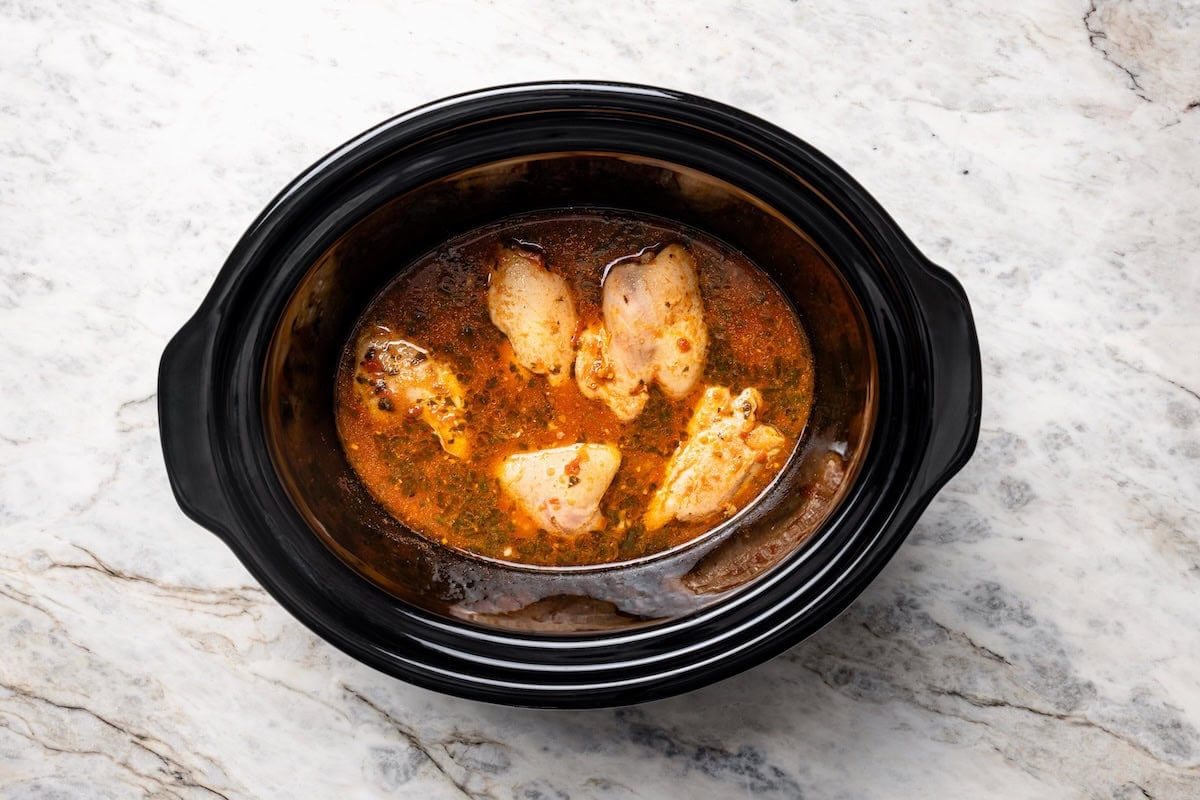 Cooked chicken breasts in salsa mixture inside the crockpot.
