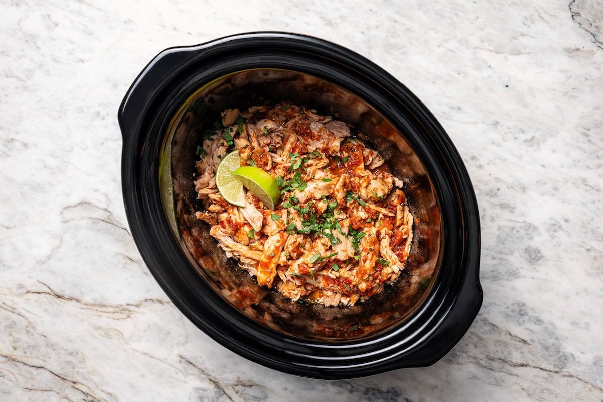 Shredded salsa chicken inside the slow cooker.