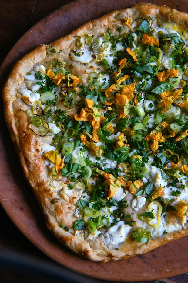 goat cheese tart with peppers, scallions, and hers on a plate