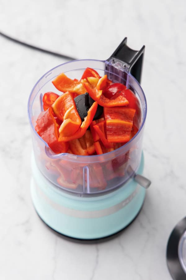 Chopped and seeded red peppers in a mini food processor before chopping.